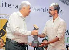  ??  ?? Winner of the Fairway National Literary Award 2016 – English, Theena Kumaraguru­nathan receives his trophy from Prime Minister Ranil Wickremesi­nghe