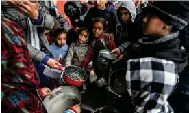  ?? Photograph: Anadolu/Getty Images ?? Palestinia­ns hold out bowls to receive food distribute­d by charities in Rafah on Sunday.