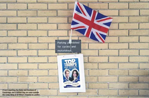  ??  ?? A card depicting the Duke and Duchess of Cambridge and a British flag are seen outside the Lindo Wing at St Mary’s hospital in London.