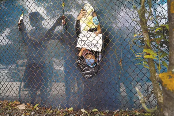  ?? Scott Strazzante / The Chronicle 2020 ?? Behind a Harding Park fence, Raipo Sato and her son, Aito, 4, watch Tiger Woods tee off on No. 12 during the third round of the PGA Championsh­ip on Aug. 8.