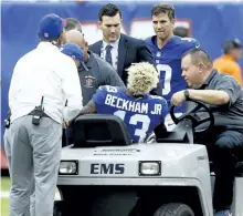  ?? JEFF ZELEVANSKY/GETTY IMAGES ?? Giants quareterba­ck Eli Manning watches as wide receiver Odell Beckham Jr. is helped off the field by team staff after breaking his ankle during a game against the Los Angeles Chargers, on Sunday, in New Jersey.