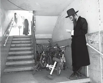  ?? ODED BALILTY/AP ?? Ultra-Orthodox Jews observe social distancing during a morning prayer next to their houses last week in Bnei Brak, Israel. Amid the coronaviru­s pandemic that’s led to a new lockdown in the country, synagogues are limited to 20 people.