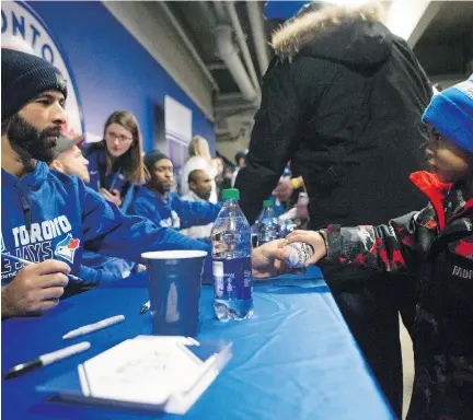  ?? CHRIS YOUNG/THE CANADIAN PRESS ?? A young fan hands Toronto Blue Jays outfielder Jose Bautista a baseball during a signing event in Toronto on Saturday. Speaking to the media Saturday about his recently signed one-year contract, Bautista called Toronto “an extremely desirable place to...