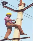  ??  ?? A WORKER installing the aerial fibre optic project, interlinke­d to the network of the two discoms in Andhra Pradesh, a file photograph.