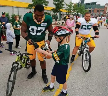  ?? MATT LUDTKE/THE ASSOCIATED PRESS ?? Packers defensive tackle Kenny Clark (97) and guard Lane Taylor ride bikes to training camp in Green Bay.