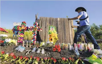  ?? ERIC GAY AP ?? Roberto Marquez of Dallas adds a flower Wednesday to a makeshift memorial at the site where officials found dozens of people dead in an abandoned semitraile­r containing suspected migrants in San Antonio.