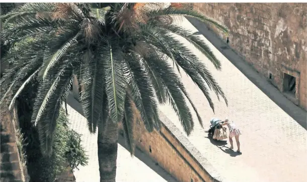  ?? FOTO: CLARA MARGAIS/DPA ?? Jeder Meter zu Fuß wird zur Qual: Diese Mutter schiebt einen Kinderwage­n einen Weg in Palma hinauf.