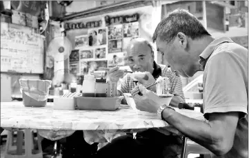  ??  ?? Two local residents eating free food at Yen noodle shop.