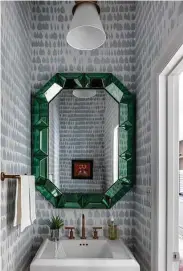  ?? ?? Schumacher wallpaper and an emerald green framed mirror gave the powder bathroom a boost.