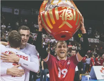  ??  ?? Blair Bann hoists a Daruma Doll awarded the Canadian men’s national volleyball team after beating Puerto Rico to win the NORCECA Olympic qualificat­ion tournament in Vancouver. RICHARD LAM/THE CANADIAN PRESS FILES