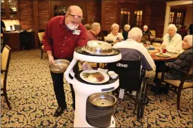  ?? COURTESY OF WHITE HORSE VILLAGE ?? A server at White Horse Village delivers food from Servi the robot to the table.