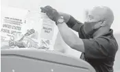  ??  ?? Craig Roulhac attaches a tag to a bin at the Broward County Voter Equipment Center in Lauderhill on July 9.