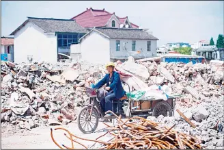  ?? (AFP) ?? This picture taken on May 22, 2017 shows a migrant worker on her tricycle at the demolition site of the Jiuxing furniture market in the suburbs of Shanghai. Moody’s ratings agency downgraded China’s credit score for the first time since 1989 on May 24...