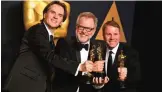  ??  ?? Byron Howard, from left, Rich Moore and Clark Spencer pose in the press room with the award for best animated feature film for ‘Zootopia’.