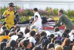  ??  ?? BANGKOK: A mourner is attended after passing out while waiting for the motorcade carrying the body of King Bhumibol Adulyadej outside the Grand Palace. —AFP