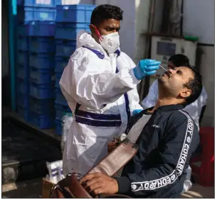  ?? (AP/Altaf Qadri) ?? A health care worker conducts random covid-19 tests Saturday in front of a shop on the outskirts of New Delhi.