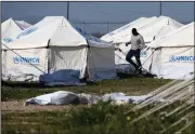  ?? (AP/Petros Karadjias) ?? A migrant walks among tents in a refugee camp Tuesday in Kokkinotri­mithia outside of Nicosia, Cyprus.