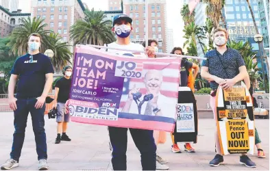  ?? FREDERIC J. BROWN / AFP VIA GETTY IMAGES ?? John Mena holds a Joe Biden flag at a rally in downtown Los Angeles on Wednesday, a day after the presidenti­al election. The result of the election is hanging on the vote count in a handful of key states, with the race too close to call.