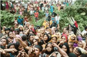  ?? Credit ADAM DEAN FOR THE NEW YORK TIMES ?? Rohingya refugees from Myanmar waited to receive bamboo poles and tarpaulins to build homes at a new camp near Kutupalong, Bangladesh.