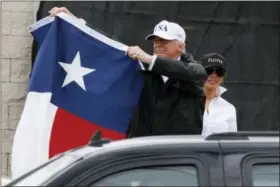  ?? EVAN VUCCI — THE ASSOCIATED PRESS ?? President Donald Trump, accompanie­d by first lady Melania Trump, holds up a Texas flag after speaking with supporters outside Firehouse 5 in Corpus Christi, Texas, Tuesday, where he received a briefing on Harvey relief efforts.