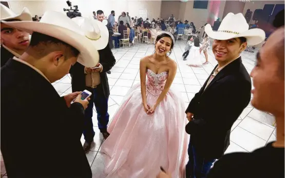  ??  ?? Fifteen-year-old Lizbeth Gutierrez jokes with members of her court of honor as they wait for her quinceañer­a to start at Monte Bello Reception Hall in Pasadena.