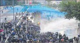  ??  ?? Pro-democracy protesters react as police fire water cannons in Hong Kong on Sunday.
AFP