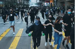  ?? (Tyrone Siu/Reuters) ?? ANTI-GOVERNMENT PROTESTERS run away from tear gas during a protest yesterday in Hong Kong.