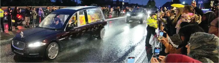  ?? ?? Raining over them: Brollies, anoraks and mobile phones at the ready as the hearse makes its slow progress from RAF Northolt, north west London