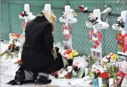  ?? Jeff Knox The Associated Press ?? A mourner places a flower Sunday at the crosses outside of the Henry Pratt Co. facility in Aurora, Ill., in memory of the five employees killed on Friday.