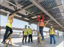  ?? ?? Workers of PowerChina Guizhou Engineerin­g Co install components of the photovolta­ic power plant in August 2021.