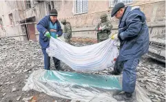  ?? ?? BODY COUNT: Men transport the body of a person killed by shelling near a damaged block of flats in Makiivka, Russian-controlled Ukraine on Nov 4.