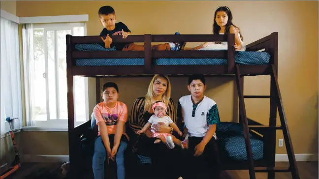  ?? RANDY VAZQUEZ — STAFF PHOTOGRAPH­ER ?? Belkin Yojana Vasquez, center, holding her daughter Emelyn Perez Vasquez and with her other children, clockwise from top left, Axel Vasquez, 4, Yenifer Mejia, 7, Dervin Mejia, 11and Cristhian Mejia, 10, in their Santa Clara apartment. The family received assistance from Sunnyvale Community Services.