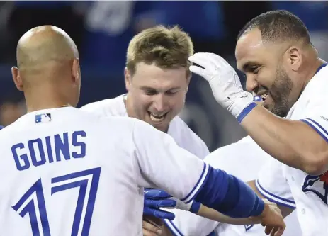  ?? NATHAN DENETTE/THE CANADIAN PRESS ?? Blue Jays designated hitter Kendrys Morales, right, is swarmed by teammates after his walk-off solo home run in the ninth inning. The Jays, down 2-0 entering the inning, tied the game on Justin Smoak’s two-run homer off Oakland closer Santiago Casilla,...