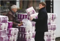  ?? (Phil Noble/Reuters) ?? PEOPLE BUY toilet rolls on sale outside a car parts shop in Manchester yesterday.