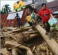  ??  ?? People walk on debris left after flash floods caused widespread distructio­n in Masamba, in Indonesia’s South Sulawesi province