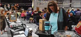  ??  ?? Pam Simpson checks out the silent auction tables during the Smithville Area Chamber of Commerce’s 21st annual Casino Night.