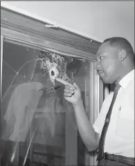  ?? (File Photo/AP/Jim Kerlin) ?? Dr. Martin Luther King Jr. looks at a glass door of his rented beach cottage June 5, 1964, in St. Augustine, Fla., that was shot into. The house connected to King is now in the hands of a couple who plans to preserve it.