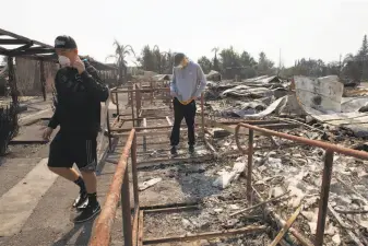  ?? Alex Washburn / The Chronicle ?? Two Cardinal Newman seniors, football player Deric Younce (left) and basketball player Tyler Botteri, check out the damage done to their Santa Rosa school by the Tubbs Fire.