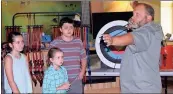  ?? / Doug Walker ?? Home-schooled students Samantha Harris (from left), 11; Sydney Harris, 8; and Dylan Scott, 12, learn how to look down the shaft of an arrow toward the target from RomeFloyd ECO Center director Ben Winkelman.