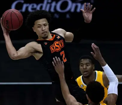  ?? Associated Press ?? Oklahoma State’s Cade Cunningham (2) passes over Baylor’s MaCio Teague in the Big 12 semifinals.