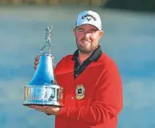  ?? AFP ?? Marc Leishman celebrates with the winner’s trophy on the 18th green after the final round on Sunday.