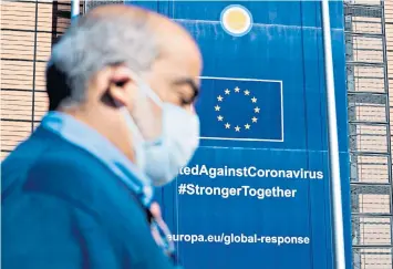  ??  ?? A man wearing a protective mask walks by the European Commission building in Brussels