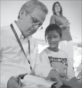  ??  ?? Mike Lupica, the author of more than 25 sports books for young readers, signs one of his works for Sachin Muralidhar of Great Falls, Virginia, at the National Book Festival in 2012. His latest, "Lone Stars," deals with football and concussion­s.