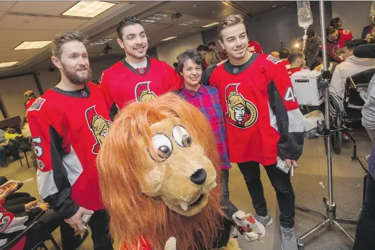  ?? WAYNE CUDDINGTON ?? Zack Smith, from left, Nick Paul and Jean-Gabriel Pageau with Spartacat and parent Jacqueline Smith as the Senators make their annual holiday visit to CHEO.