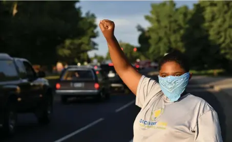  ??  ?? Dayvion Crowe, 14, raises a fist as vehicles move in a caravan during the “Defend Black Life Car Rally” that left from Shorter Community AME Church in Denver on Thursday. The caravan was organized by Black Lives Matter 5280 to help people protest while maintainin­g social distance.