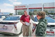  ??  ?? Vehicle shopper Mary Jean Jones speaks with Mark Miller Toyota salesman Doug Lund, in Salt Lake City. Auto sales are slowing from last year’s record pace, causing some automakers to cut jobs.