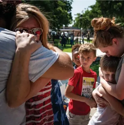  ?? © ?? Kinderen van de school in Uvalde en hun ouders rouwen nabij de kruisen met de namen van de slachtoffe­rs erop. nyt