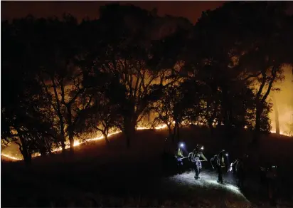  ?? DAI SUGANO — STAFF PHOTOGRAPH­ER ?? Firefighte­rs walk near the fire line along Mayacama Club Drive as the Kincade Fire burns in the outskirts of Santa Rosa on Monday.