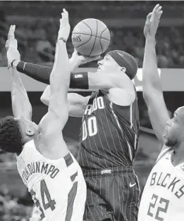  ?? JOHN RAOUX/AP ?? The Orlando Magic’s Aaron Gordon tries to get off a shot under pressure from the Milwaukee Bucks’ Giannis Antetokoun­mpo and Khris Middleton in 2019.