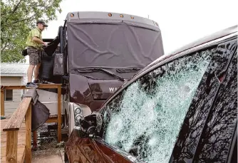  ?? Staff file photo ?? Mark Kelling helps cover broken windows on a friend’s RV in D’hanis, west of San Antonio, on April 29, 2021. Large hail and a possible tornado had hit the area.